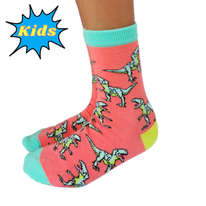 CLASSIC JURASSIC SOCKS - KIDS'. Pink background with t-rex pattern all over the socks. Teal toes and top of socks with lime green heal.
