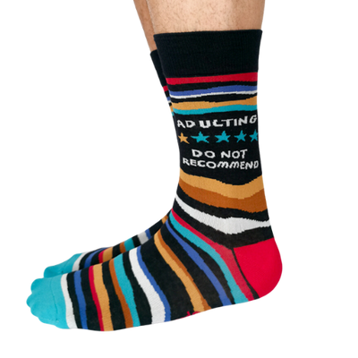 A close-up of Uptown Sox's Adulting Socks featuring funny illustrations and phrases about the challenges of adult life, perfect for anyone who can relate to the ups and downs of growing up.